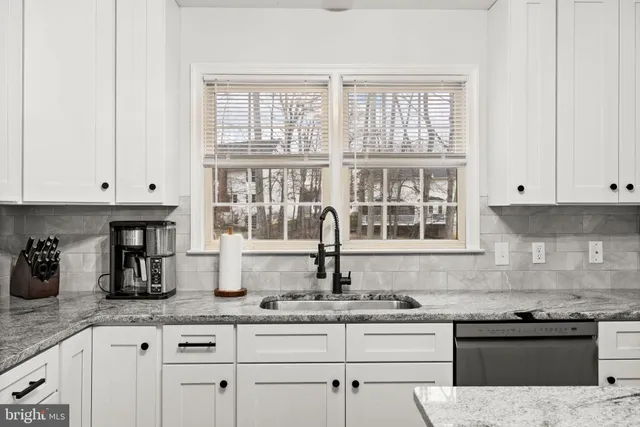 a kitchen with granite countertop a sink white cabinets and a window
