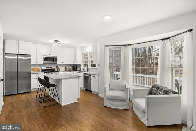 a kitchen with stainless steel appliances granite countertop a refrigerator a stove top oven a sink dishwasher and white cabinets with wooden floor