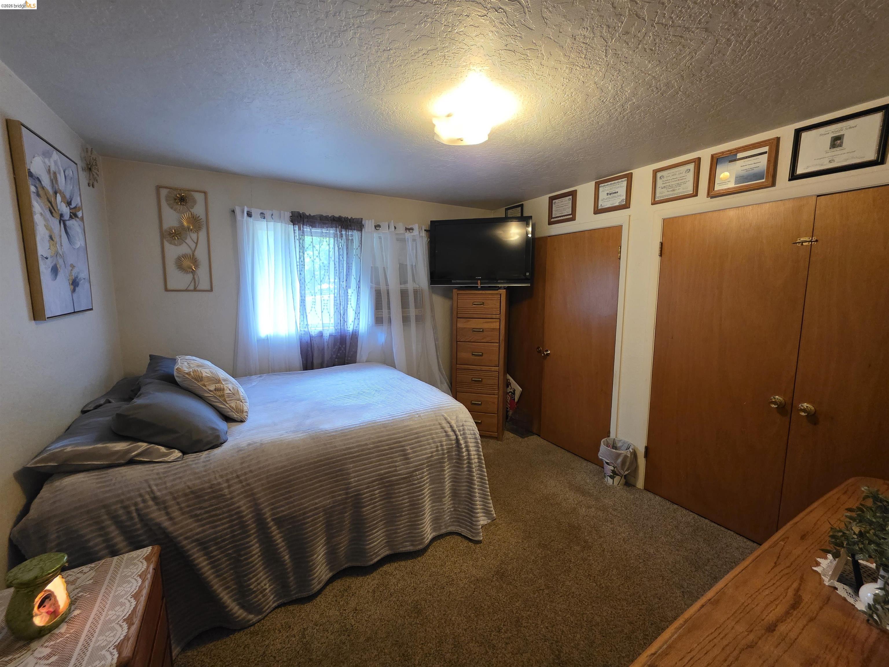 2323 Spink Road West Point, CA 95255 - Photo 13 of 17 Carpeted room featuring a window with sheer curtains, two built-in closet units with wood doors, and a ceiling-mounted light fixture