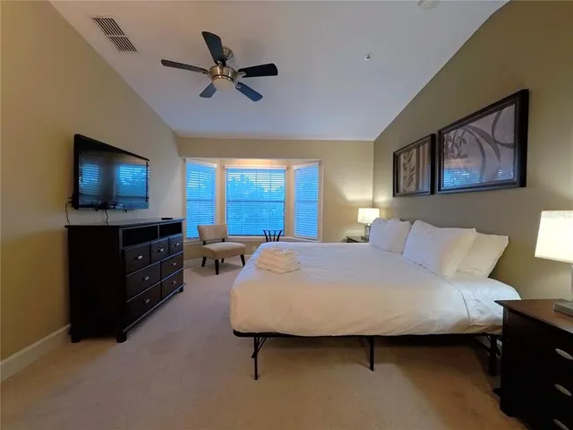 a spacious bedroom with a bed and a flat screen tv