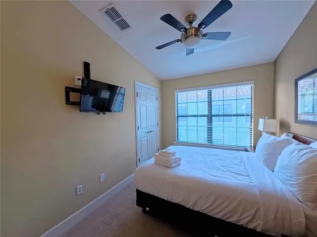 a bedroom with a bed a window and a flat screen tv