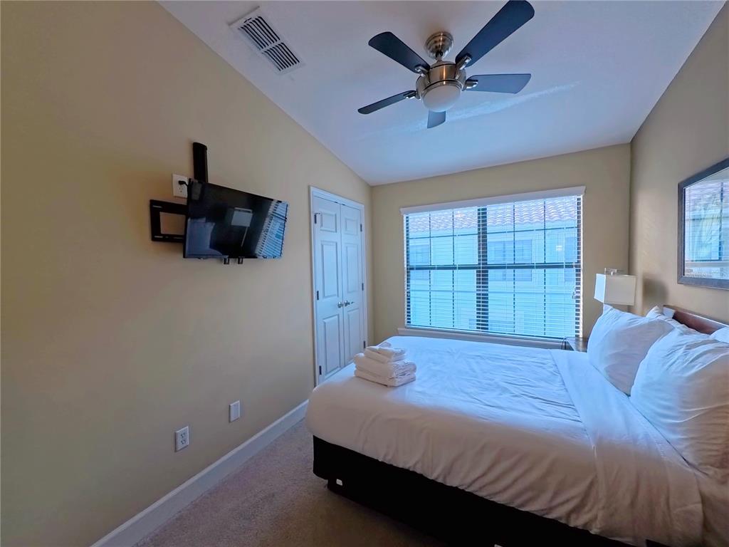 14525 Damai Lane Orlando, FL 32821 - Photo 20 of 30 a bedroom with a bed a window and a flat screen tv