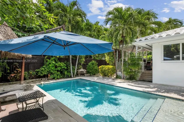a view of pool with lawn chairs under an umbrella