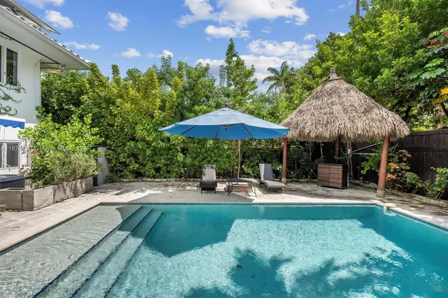 a backyard of a house with table and chairs under an umbrella