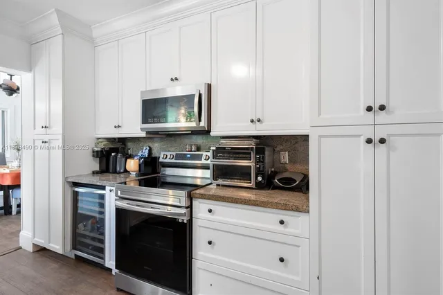 a kitchen with stainless steel appliances granite countertop white cabinets and a stove a refrigerator with white cabinets