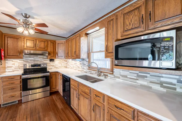a kitchen with stainless steel appliances granite countertop a sink dishwasher stove and refrigerator with wooden floor