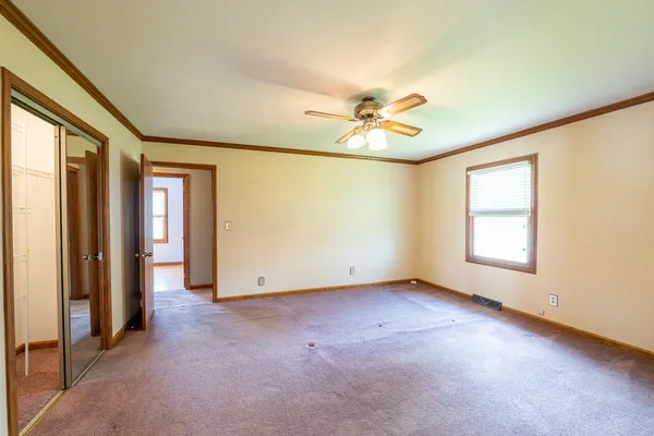 an empty room with chandelier fan and windows