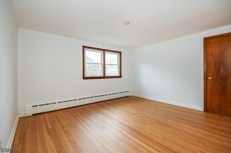 13 Knapp Avenue Clifton, NJ 07011 - Photo 12 of 17 an empty room with wooden floor and windows