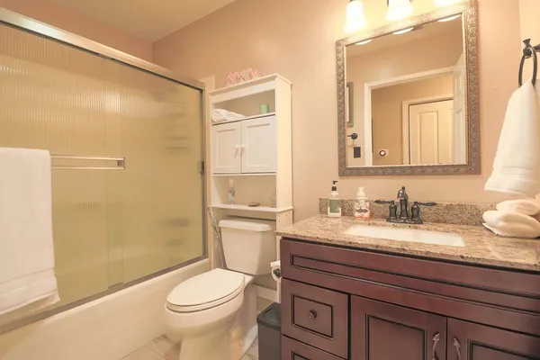 a bathroom with a granite countertop sink toilet and shower