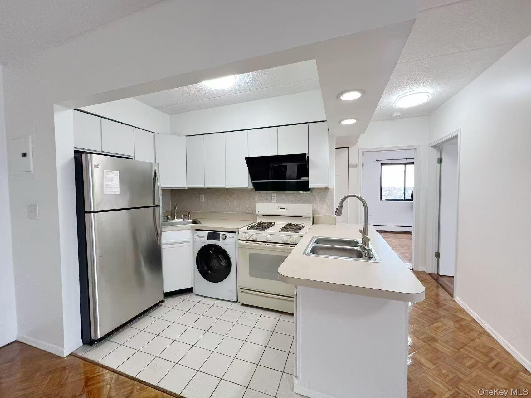 54-09 108th Street, Unit 6A Queens, NY 11368 - Photo 2 of 14 Kitchen with a peninsula, freestanding refrigerator, white gas stove, light countertops, and washer / clothes dryer