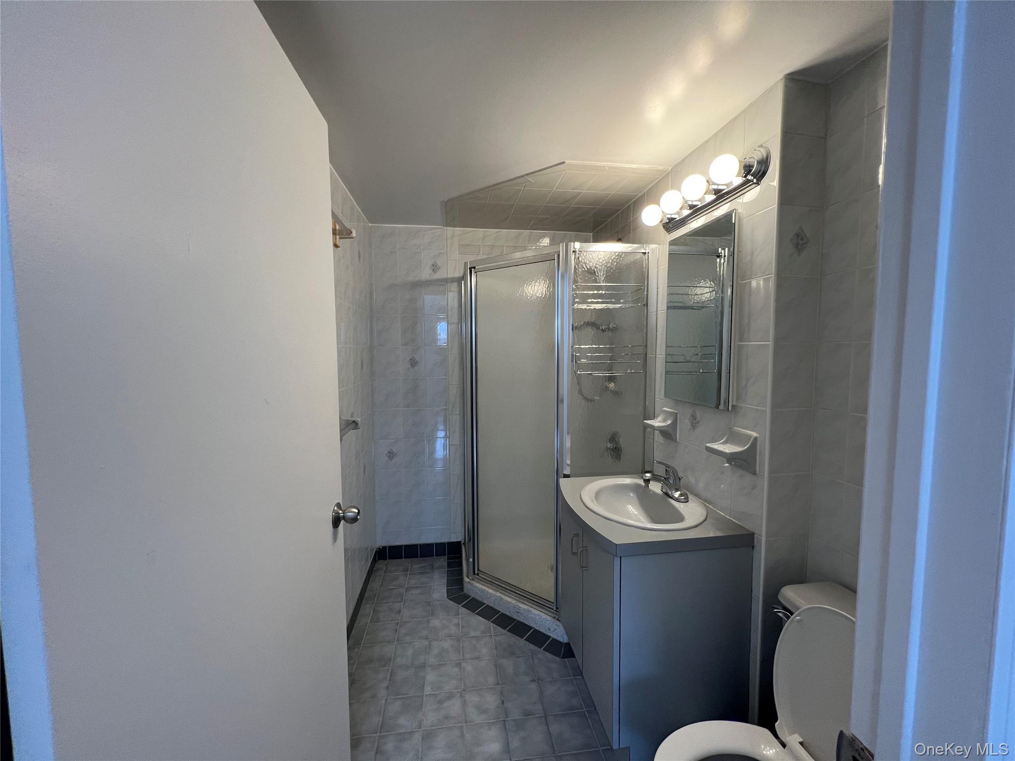 54-09 108th Street, Unit 6A Queens, NY 11368 - Photo 10 of 14 Full bathroom featuring vanity, a stall shower, and light tile patterned flooring