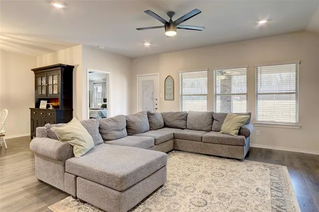 a living room with furniture kitchen view and a wooden floor