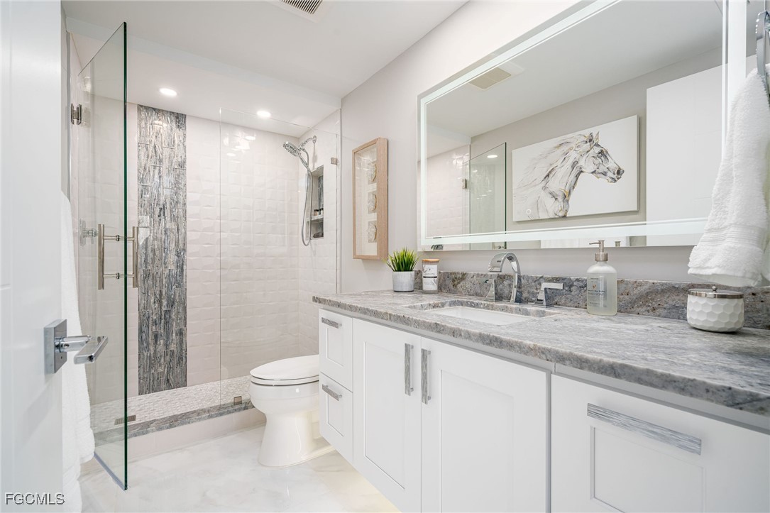 17 Bluebill Avenue, Unit 903 Naples, FL 34108 - Photo 19 of 33 a bathroom with a granite countertop sink a toilet and a shower