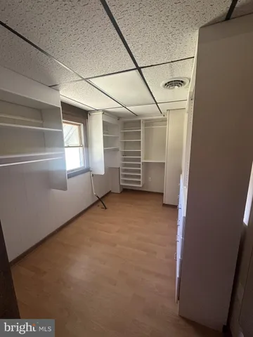 a view of an empty room with wooden floor and windows
