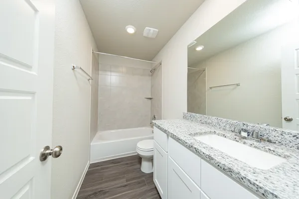 a bathroom with a granite countertop sink a toilet a mirror and shower