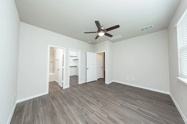 an empty room with wooden floor and windows