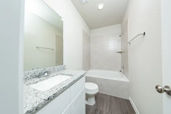 a bathroom with a granite countertop sink a toilet and shower