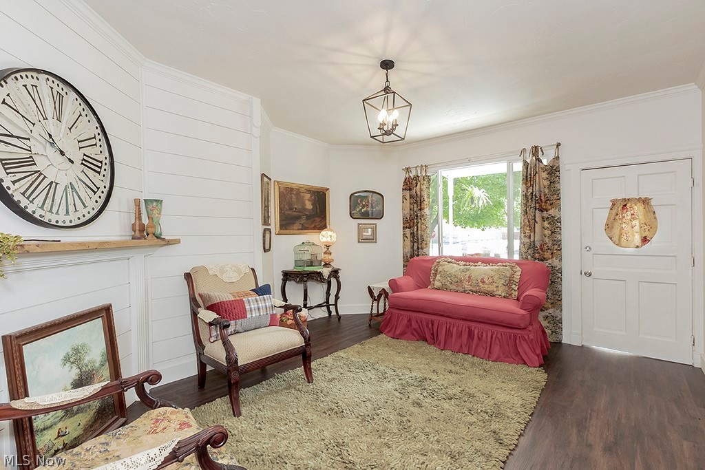 Sitting room featuring a chandelier, crown molding, and dark wood-type flooring