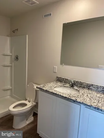 a bathroom with a granite countertop sink toilet and shower