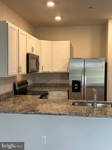 a kitchen with stainless steel appliances granite countertop a sink a stove and a refrigerator