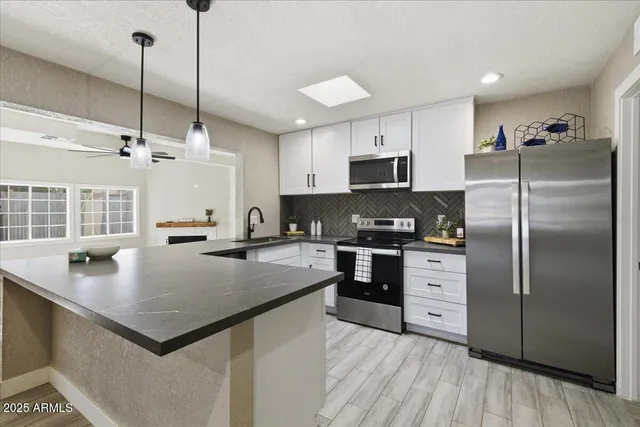 a kitchen with stainless steel appliances granite countertop a refrigerator a stove a sink dishwasher and a refrigerator with wooden floor