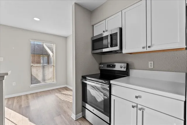 a kitchen with white cabinets stainless steel appliances and wooden floor