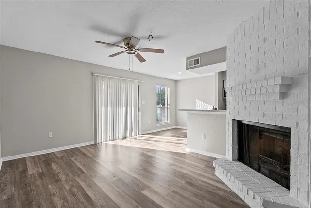 a view of empty room with wooden floor and fireplace