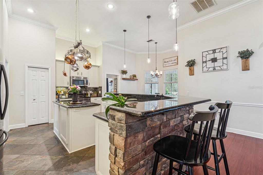 3077 Cork Road Plant City, FL 33565 - Photo 23 of 99 a kitchen with stainless steel appliances granite countertop a stove a refrigerator a kitchen island with a dining table and chairs