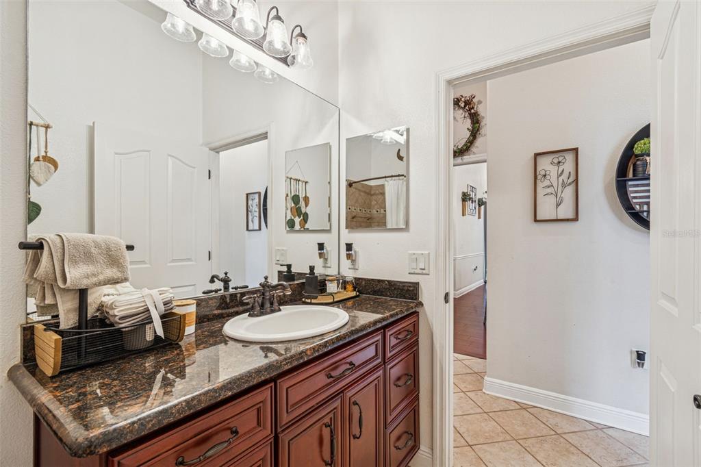 3077 Cork Road Plant City, FL 33565 - Photo 53 of 99 a bathroom with a granite countertop sink a mirror and a shower