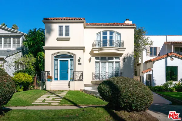 a view of a white house with a small yard and plants