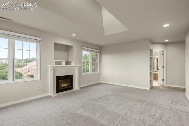 an empty room with windows and fireplace