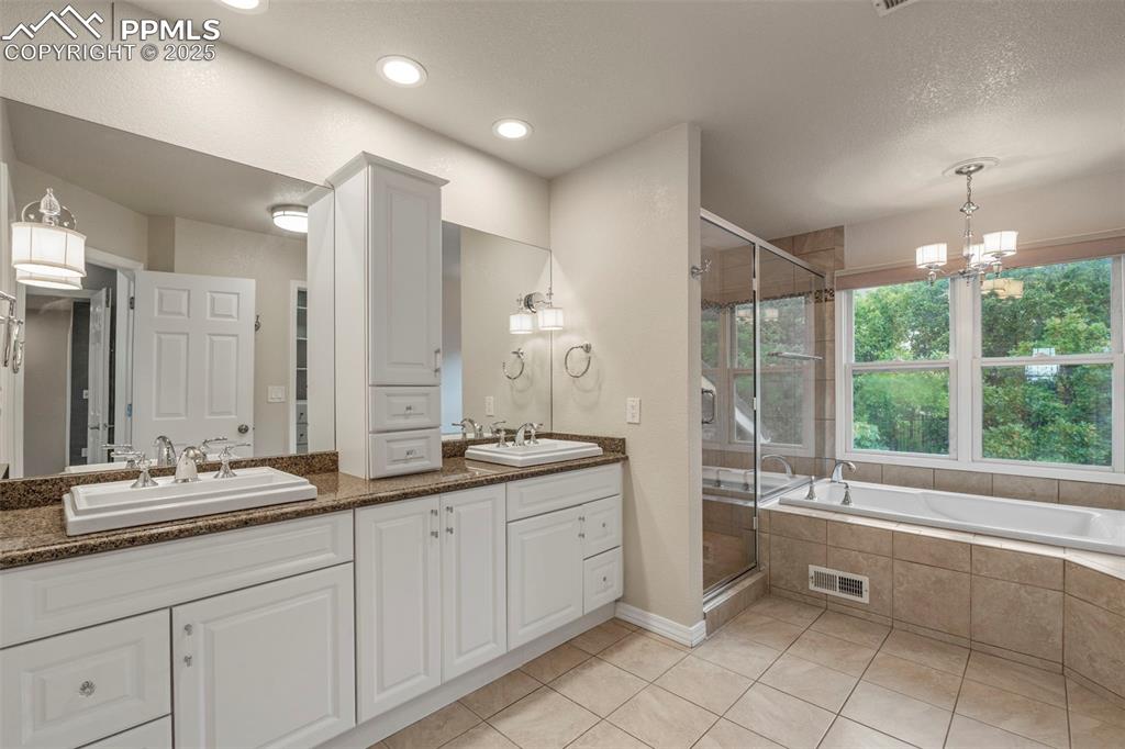4930 Langdale Way Colorado Springs, CO 80906 - Photo 24 of 49 a spacious bathroom with a double vanity sink a large mirror and a bathtub