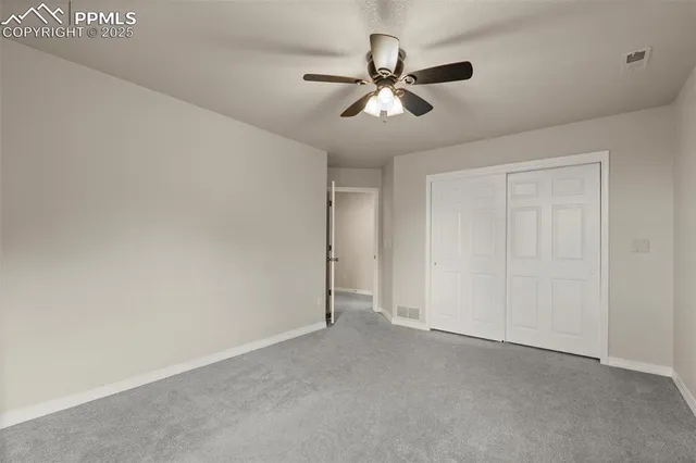 a view of an empty room and chandelier fan