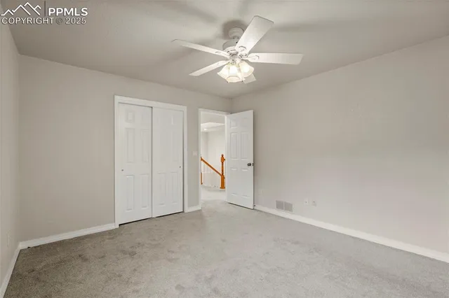a view of an empty room and chandelier fan