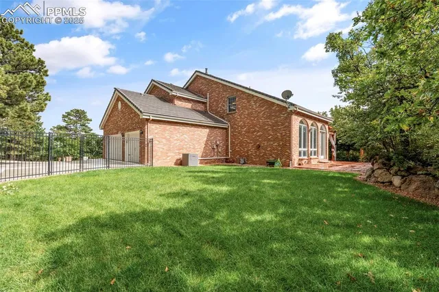 a brick house with a big yard and large trees