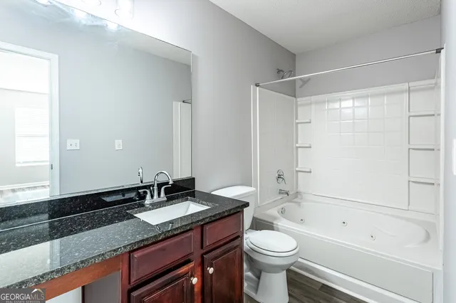 a bathroom with a granite countertop sink toilet a large mirror a bathtub and shower