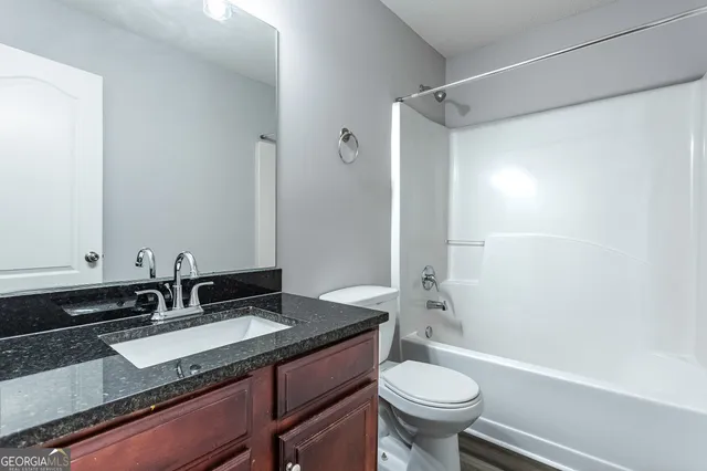 a bathroom with a granite countertop sink toilet a mirror and shower