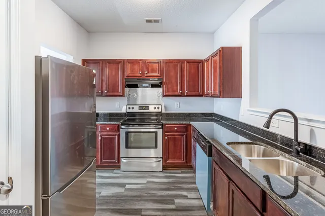 a kitchen with stainless steel appliances granite countertop a sink stove and refrigerator