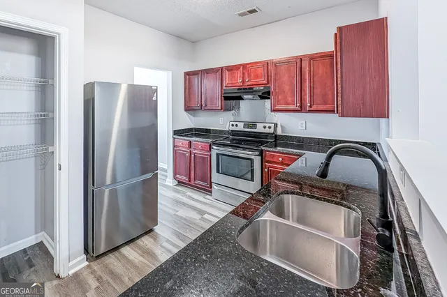 a kitchen with stainless steel appliances granite countertop a refrigerator sink and stove