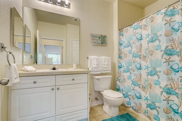 a bathroom with a granite countertop toilet a sink a mirror and a shower curtain