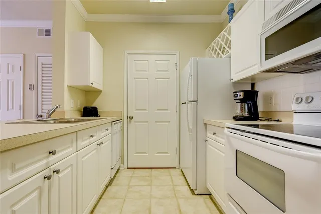 a kitchen with white cabinets and appliances