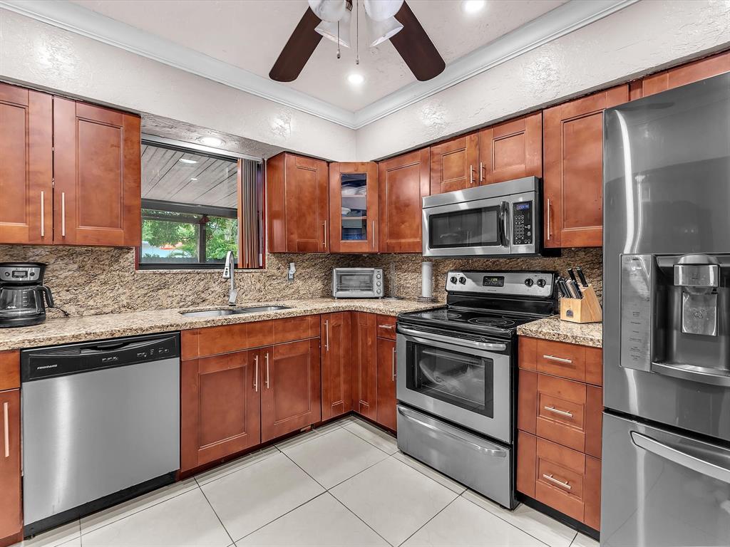 6631 Southwest 24th Street Miramar, FL 33023 - Photo 15 of 42 a kitchen with stainless steel appliances granite countertop a stove top oven a sink and a microwave
