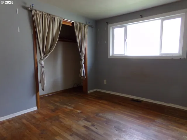 an empty room with wooden floor and a window