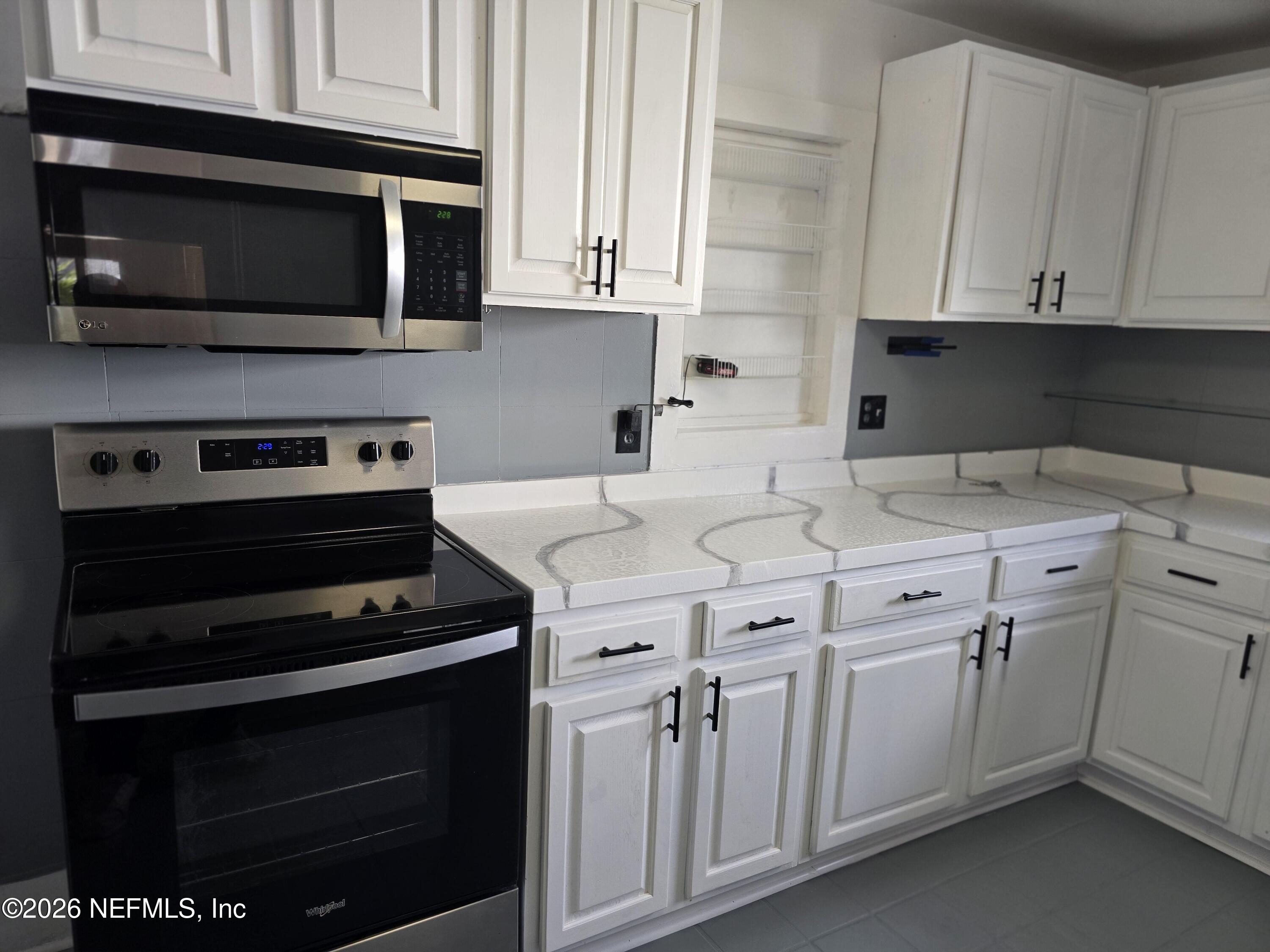 4710 Springfield Boulevard Jacksonville, FL 32206 - Photo 17 of 28 a kitchen with white cabinets stainless steel appliances and sink