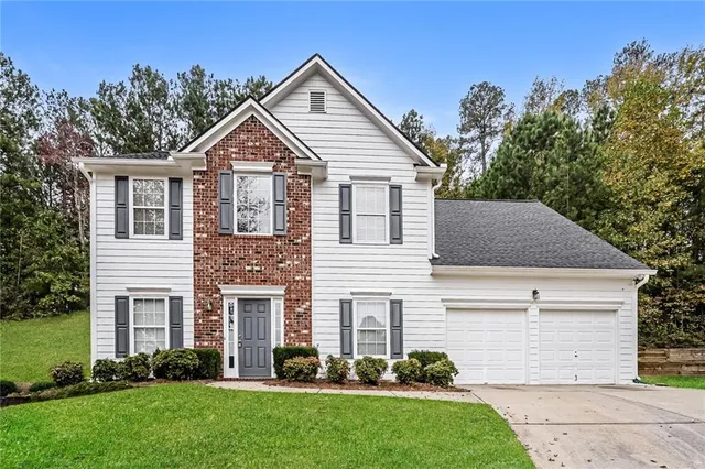 a view of a yard in front of a house with plants and large tree