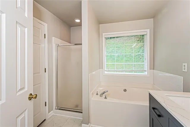 a bathroom with a tub a sink a window and a shower