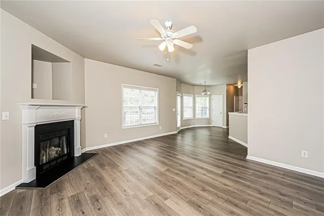 an empty room with wooden floor fireplace and windows
