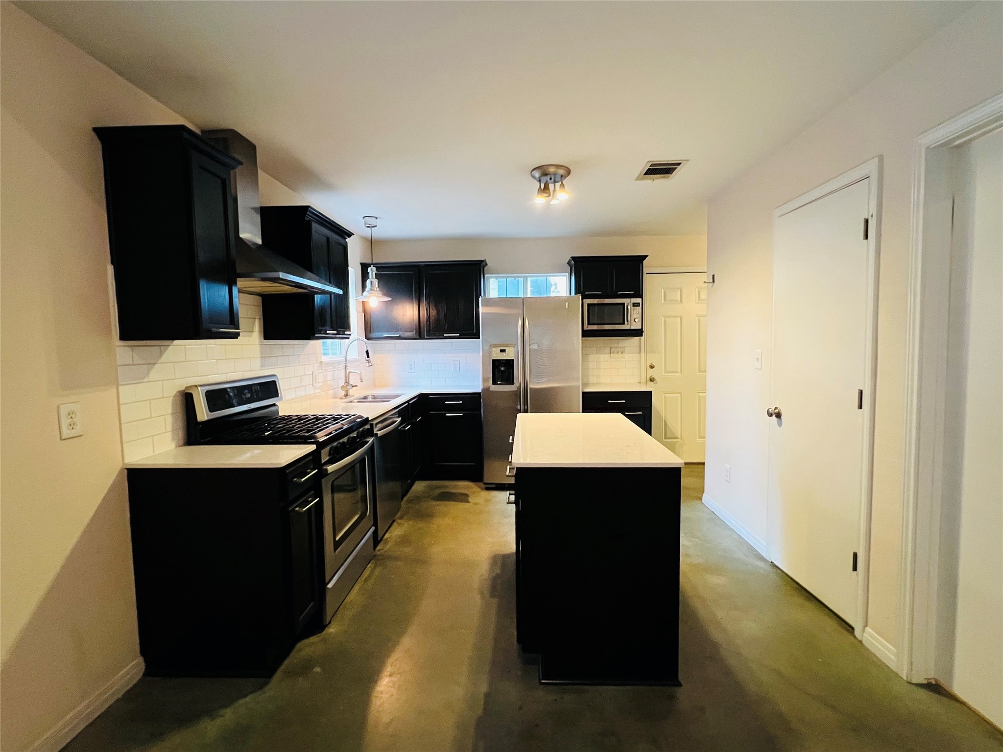 2409 Santa Rosa Street Austin, TX 78702 - Photo 5 of 27 Contrast abounds with dark cabinetry against bright countertops and smooth concrete flooring.