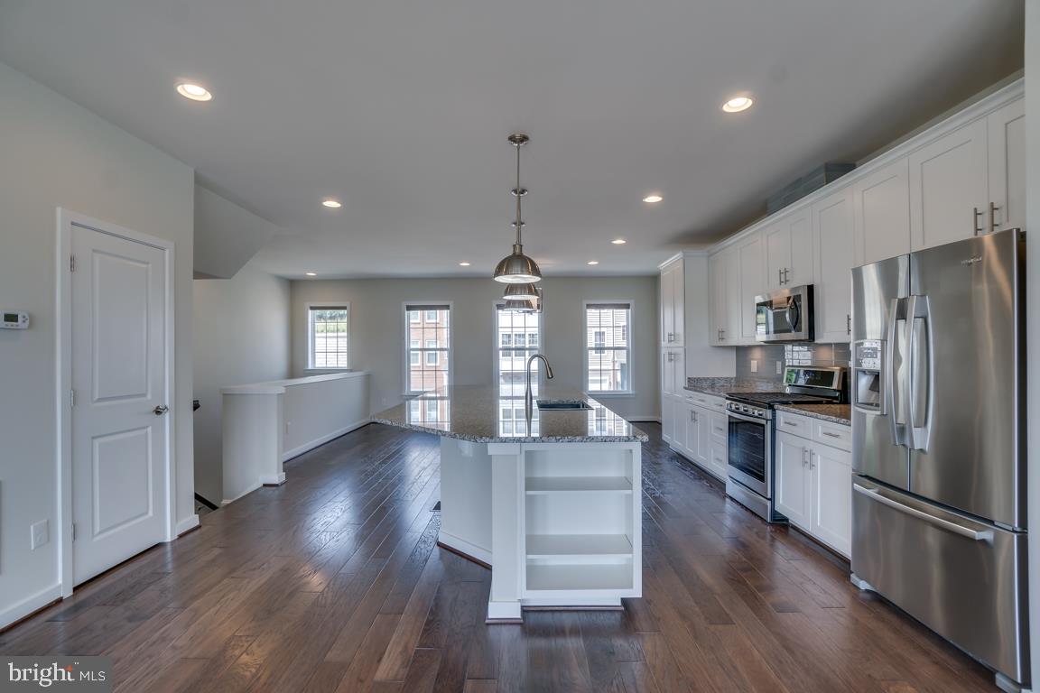 19958 Abram Terrace Ashburn, VA 20147 - Photo 5 of 41 a kitchen with stainless steel appliances granite countertop a refrigerator a sink dishwasher a stove and white countertops with wooden floor