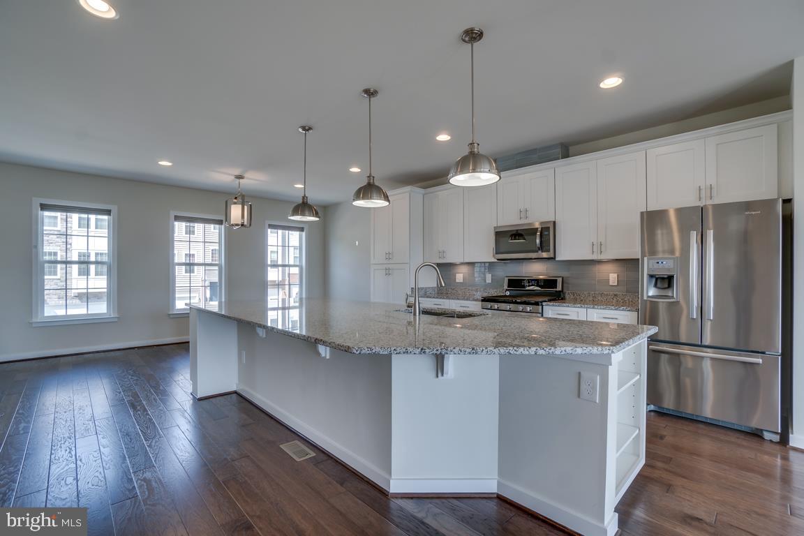 19958 Abram Terrace Ashburn, VA 20147 - Photo 6 of 41 a kitchen with stainless steel appliances granite countertop a refrigerator a sink dishwasher a kitchen island with wooden floor and cabinets